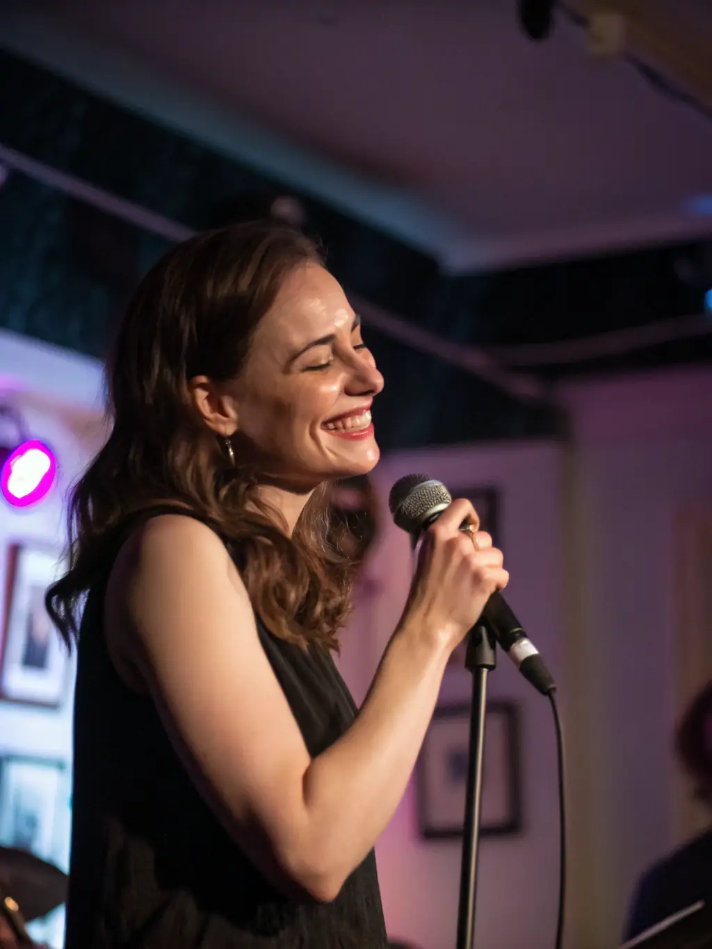 A vibrant image of a singer performing on stage with a classic French ambiance, featuring warm lighting and an engaged audience.